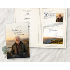 Quiet Shore bifold funeral program mockup on linen, folded cover with a full-bleed coastal photo of an older bearded man beside the open inside spread.